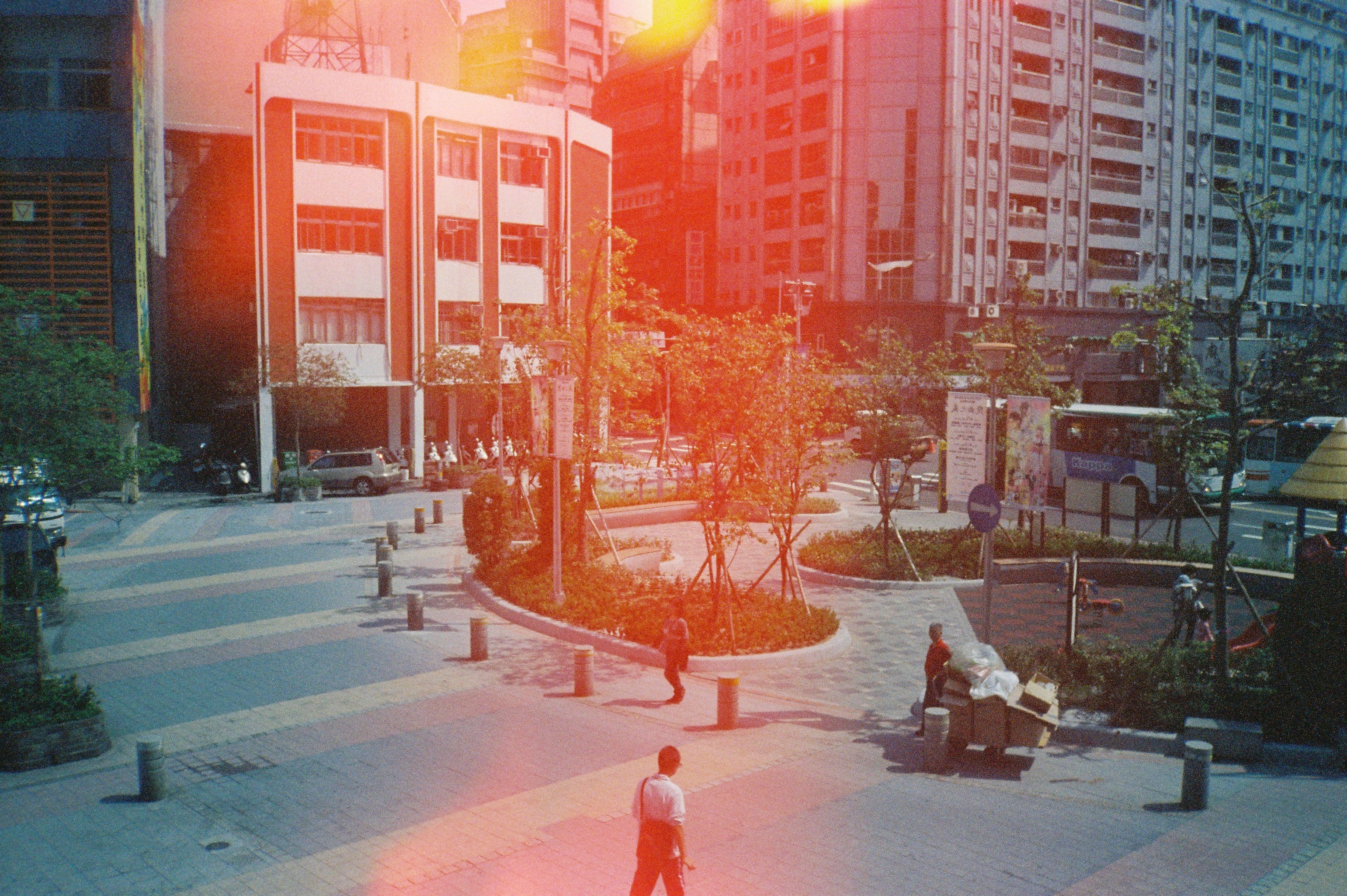 A film photo of a person walking through a courtyard in Japan that has a red lens glare covering the photo.